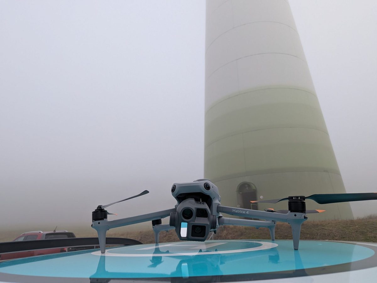 Inspektionsdrohne auf einer Startplattform vor dem Turm einer Windenergieanlage