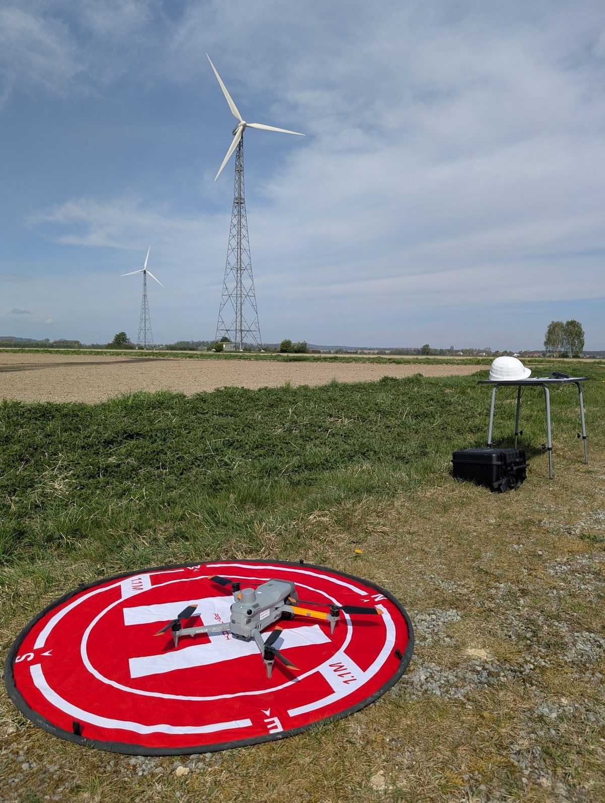 Drohne auf Landepad vor Windenergieanlagen